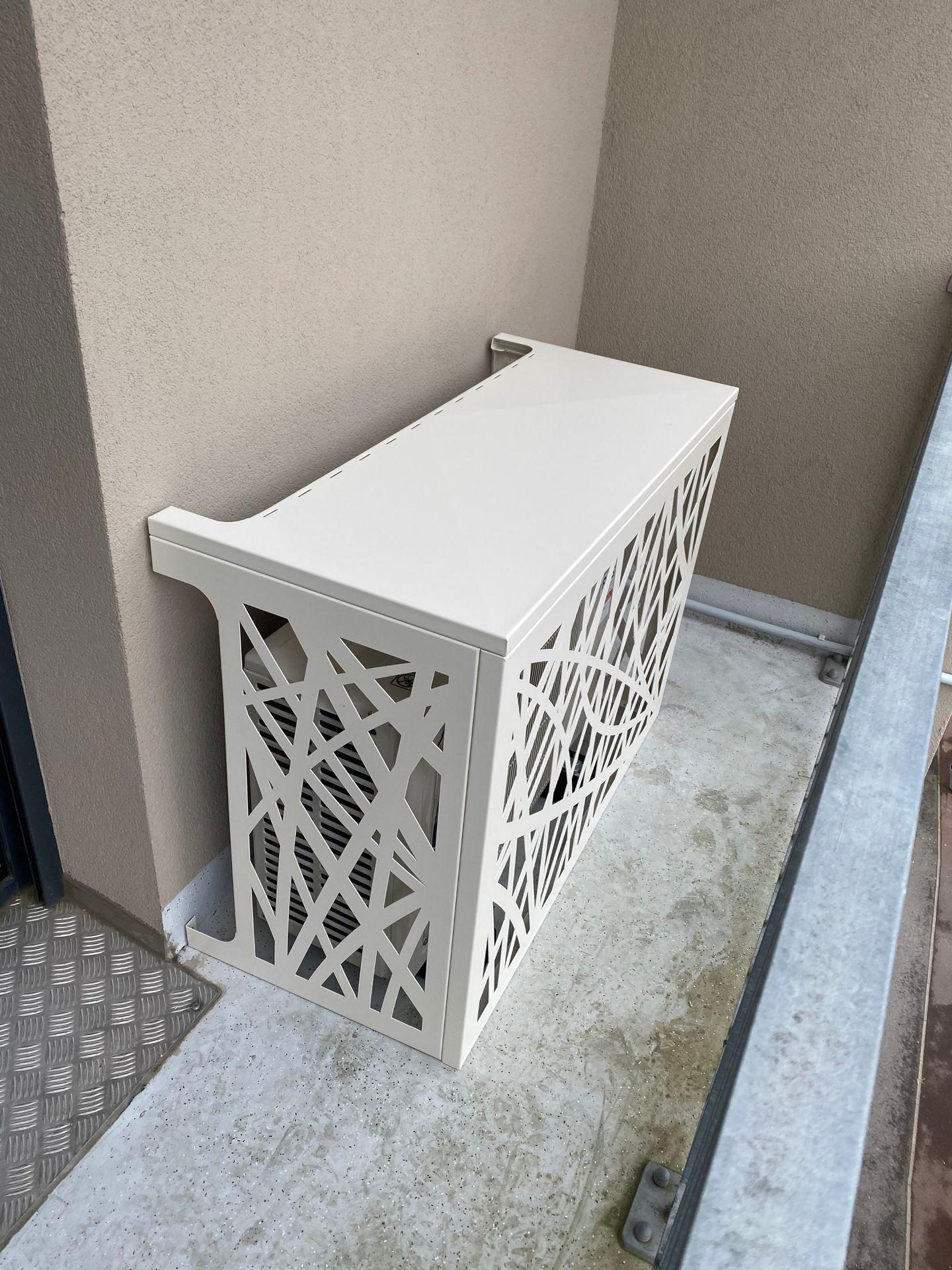 Groupe extérieur de climatisation habillé d'un caisson ajouré sur un balcon